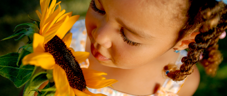 young girl smelling a sunflower, Minnesota mental health clinics, ccbhc Minnesota