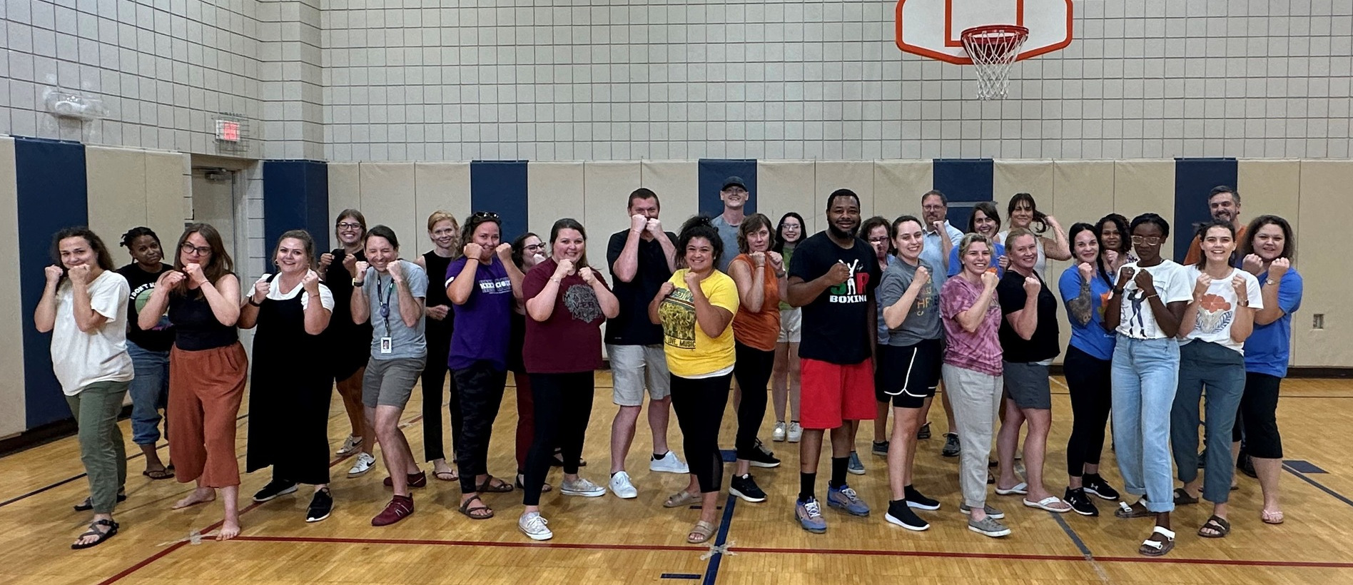 TAP team posing in a gymnasium underneath a basketball hoop